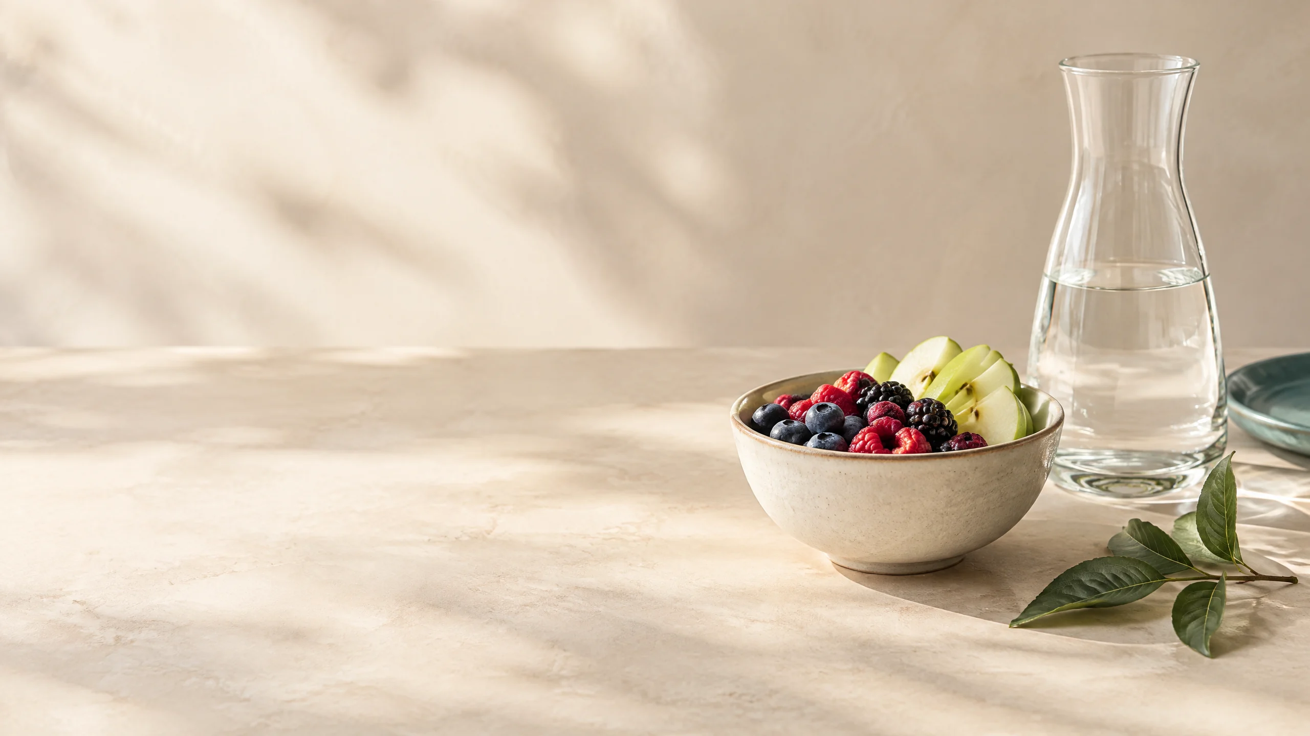 Schale mit Beeren und Obst neben einer Karaffe Wasser